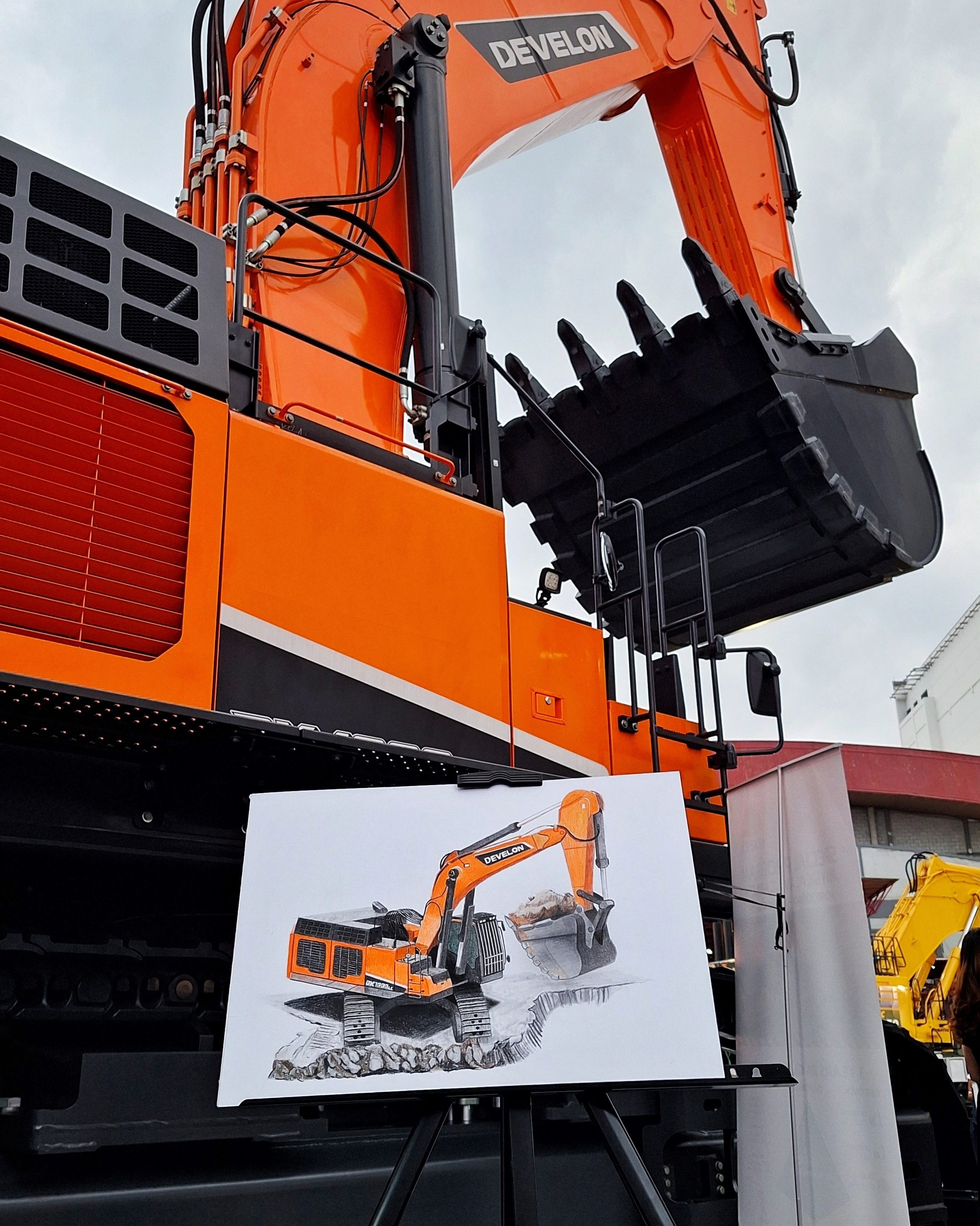 Live drawing performance for Develon Asia, a finished excavator drawing propped against the real machine